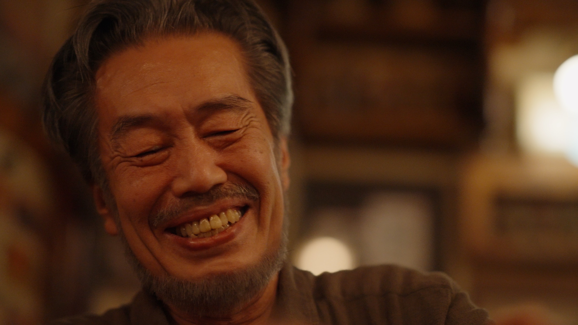 The artist Shinko Yamaguchi laughing in the warm light of the bar